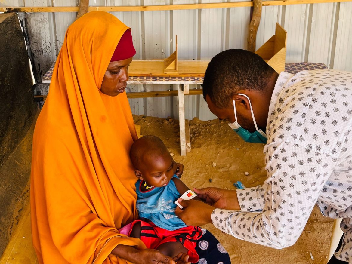 Somalia, Gesundheitszentrum in Bentiu, Mutter mit Kleinkind, Mann untersucht Kleinkind
