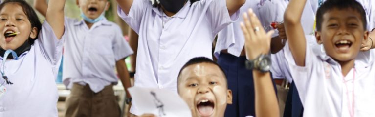 Mehrere Schüler:innen halten mit Freude ihre Zeichnungen in die Höhe.