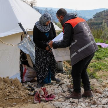 CARE Partner verteilt Hygiene-Kits an eine vertriebene Frau vor ihrem Zelt in einem Lager für Binnenvertriebene in Syrien.