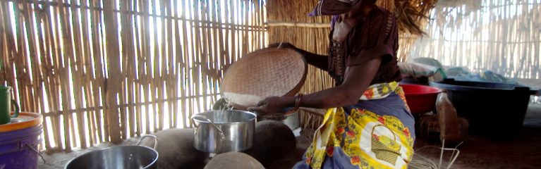 Mosambik (Ostafrika). Cecilia in ihrer sicheren und trockenen neuen Unterkunft im Flüchtlingscamp. CARE und die Partnerorganisation Shelterbox haben die Menschen, die vor der ausbrechenden Gewalt in Cabo Delgado vor sechs Jahren geflohen sind, mit lebenswichtigen Grundprodukten versorgt. Cecilia bereitet mit den erhaltenen Kochutensilien Reis in ihrem neuen Zuhause zu.
