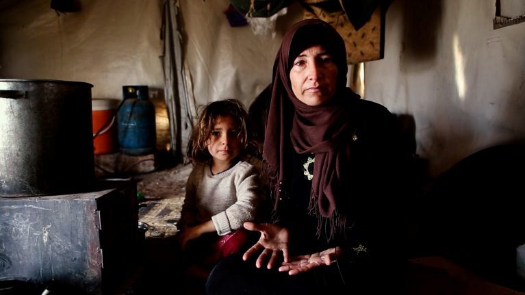 Winterhilfe für Syrien. Die Vorbereitungen laufen. Hier im Bild Mutter Um-Ahmed mit ihrer kleinen Tochter. Sie sitzen im provisorischen Zelt vor ihrem Ofen. Kinder und Familien haben es besonders schwer im kalten Winter.