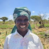 Strahlende Bäuerin mit grünem Kopftuch vor bewässertem Gemüsegarten - CARE Österreich Frauen-Landwirtschaft und Bewässerungsprojekte