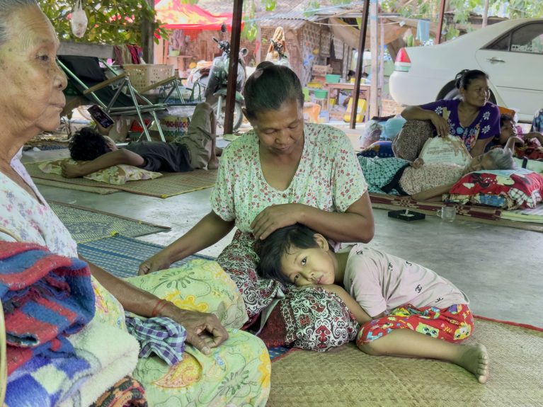 Notunterkunft nach Erdbeben in Myanmar mit Frauen und Kindern auf Bodenmatten ruhend
