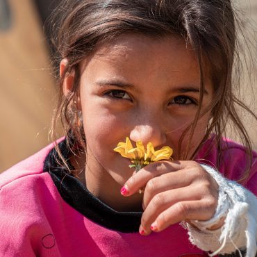 Junges Mädchen in pinkem Pullover mit bandagierter Hand; CARE Österreich unterstützt Kinder in Not.