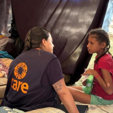 CARE-Helferin spricht in einer provisorischen Zeltunterkunft in Venezuela mit einem Mädchen, das vom Erdbeben betroffen ist, und bietet psychosoziale Unterstützung im Rahmen der CARE-Katastrophenhilfe mit Nahrung, Trinkwasser, Hygieneartikeln und Notunterkünften.