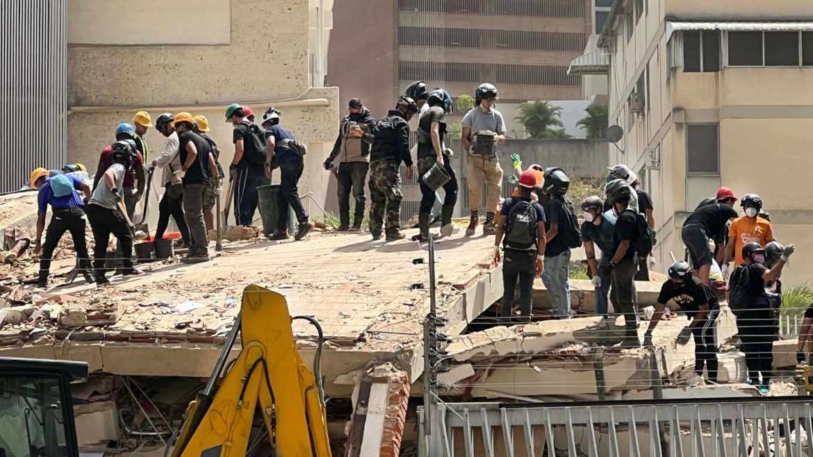 Rettungskräfte und freiwillige Helfer stehen auf den Trümmern eines eingestürzten Gebäudes nach einem Erdbeben in Venezuela und suchen nach Verschütteten; CARE und lokale Partner leisten Katastrophenhilfe.