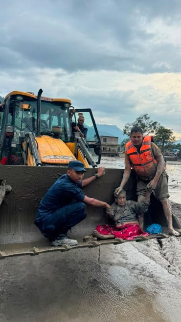 Rettungskräfte retten ältere Frau aus Flutkatastrophe mit Bagger – Notfallrettung bei Hochwasser in Bergregion